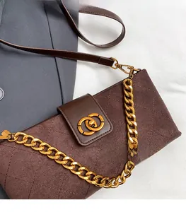 Detailed view of brown quilted suede shoulder bag featuring a gold chain and metal buckle