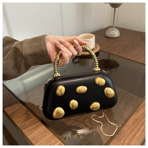 Details einer schwarzen Lederhandtasche mit kunstvollen, goldenen Metallverzierungen