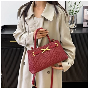 Détail macro du sac en cuir tressé bordeaux avec fermoir en X doré et texture luxe