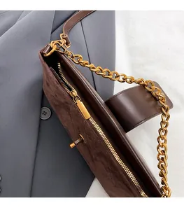 Detail of dark brown leather crossbody bag with gold chain strap and suede texture
