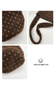 Detailed close-up of brown plush shoulder bag featuring white polka dots and stitching