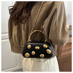 Details der schwarzen Ledertasche mit goldenen Kiesel-Akzenten und einer Metallkette