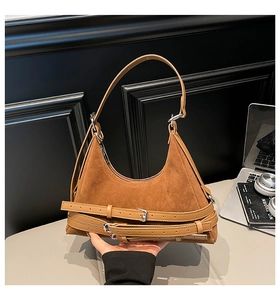 Dettaglio della borsa a spalla in pelle scamosciata marrone con tre fibbie e finiture metalliche