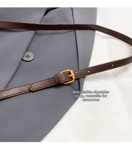 Close-up of brown leather adjustable shoulder strap with gold metal buckle and detail