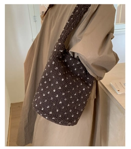 Detail of plush brown bucket bag with white polka dots worn with a tan trench coat