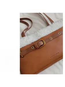 Gros plan détaillé du sac à bandoulière marron avec bordure en polaire et boucle en métal
