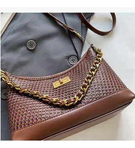 Gros plan d'un sac hobo tressé marron avec chaîne dorée et fermoir pivotant
