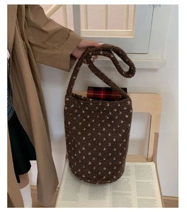 Close-up of brown plush bucket bag with white polka dots and plaid lining detail