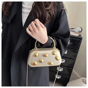 Detailansicht der champagner-goldenen Clutch mit Kieselmetall-Akzenten und Spiralgriff