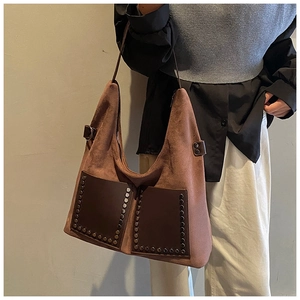 Close-up of brown suede hobo bag featuring vintage metal rivets and leather pockets