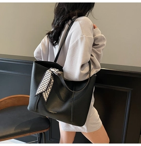 Detail of black pebbled leather tote with fashion gold text and check silk scarf