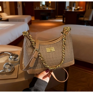 Gros plan d'un sac bandoulière pied-de-poule avec chaîne dorée et fermoir rotatif chic
