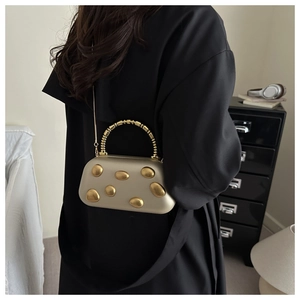 Champagner-Abendtasche mit kieselartigen Metallakzenten im Crossbody-Stil getragen