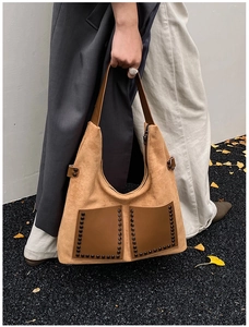 Gros plan d'un cabas en daim marron avec poches en cuir et rivets décoratifs noirs