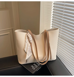 Detail of cream tote bag with lychee texture, brown straps, and decorative floral scarf