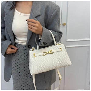 Détail d'un sac à main blanc tressé avec boucle dorée et bandoulière amovible