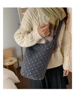 Detail of plush grey shoulder bag with white polka dots on a soft knit sweater