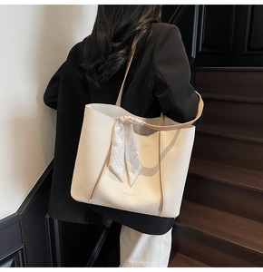 Macro view of cream tote bag featuring lychee grain leather and elegant printed scarf