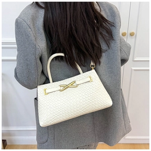 Gros plan du sac seau blanc en cuir tressé avec fermoir doré en X et détails noués
