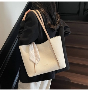 Close-up of cream tote bag featuring litchi texture and decorative geometric scarf