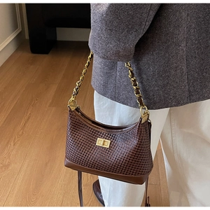 Détail du sac tressé marron foncé avec bandoulière chaîne dorée et fermoir métallique