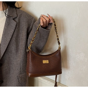 Détail d'un sac en cuir tressé marron avec chaîne dorée et fermoir rotatif métallique
