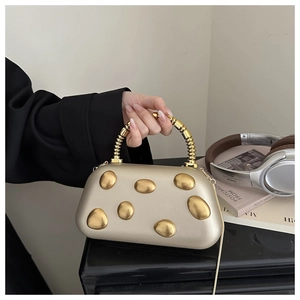 Detail of champagne gold evening bag with metallic decor and spiral metal handle