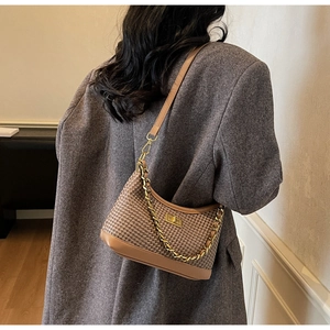Détail du sac porté épaule tissé avec chaîne dorée et bandoulière en cuir sur un modèle