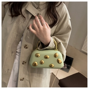 Detail der mintgrünen Clutch mit goldenen Kieselmetall-Akzenten und Spiralfedergriff am Mantel