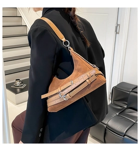 Dettaglio della borsa sottobraccio in pelle scamosciata caramello con fibbie metalliche