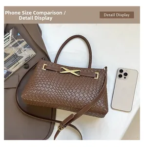 Détail de la texture tressée marron foncé du sac à main avec boucle métallique dorée en X