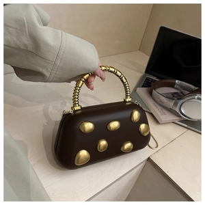 Detailed close-up of dark brown leather handbag with gold textured metal ring handle