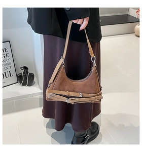 Dettaglio borsa a mezzaluna in camoscio marrone con fibbie argento e texture hobo