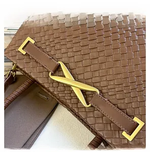 Détail de la boucle en métal doré en X sur le sac à main tressé en cuir marron foncé