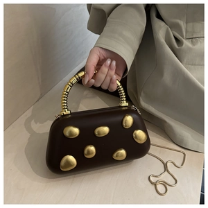 Close-up of brown evening bag with irregular gold pebble accents and spiral metal handle