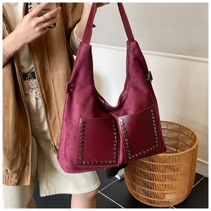 Détail macro du sac hobo en daim bordeaux avec rivets vintage et deux poches frontales