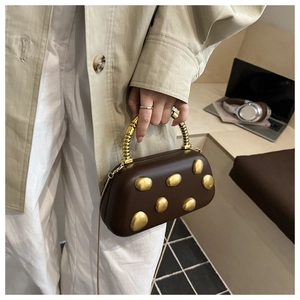 Detail of a dark brown vintage shoulder bag with golden studs and spiral metal handle