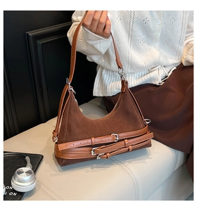 Dettaglio borsa a mezzaluna in camoscio marrone con cinturini decorativi e fibbie in pelle