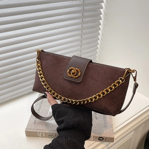 Deep brown quilted crossbody bag with gold chain and circular lock on white table