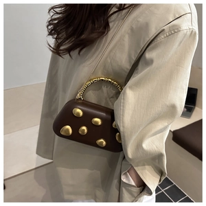 Detailed macro view of smooth dark brown leather handbag with gold oval metal ornaments
