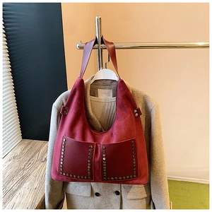 Détail d'un sac cabas vintage bordeaux avec rivets en bronze et texture en daim