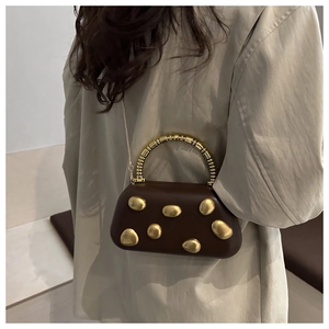 Detail view of a dark brown leather bag with golden pebble accents and chain strap