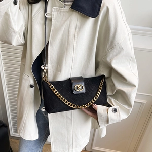Classic black quilted crossbody bag with gold chain strap shown on a white trench coat