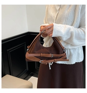 Dettaglio della borsa sottobraccio in tela marrone con cinturini in pelle e fibbie argento