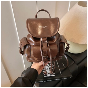Detail view of dark brown faux leather backpack with front pockets and buckle closure