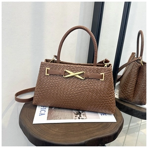 Détail de la texture tressée marron et boucle dorée en X sur un sac à main rétro