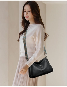 Close-up of black lychee grain leather crossbody bag with ethnic jacquard wide strap