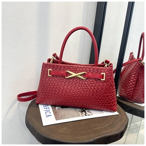 Détail du sac tressé rouge avec fermoir doré en X sur un tabouret vintage
