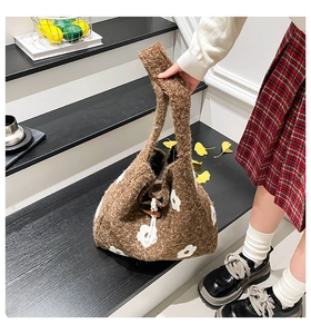 Detail of wool knit shoulder bag featuring white floral patterns and wood button closure