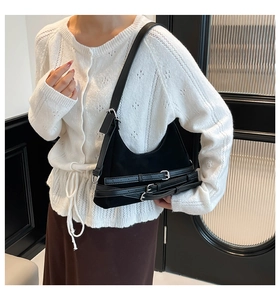 Dettaglio borsa sottobraccio nera opaca con fibbie metalliche e stile biker moderno